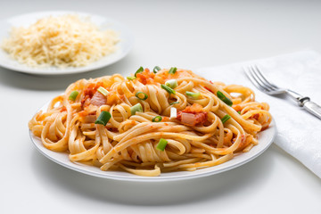 Spaghetti with tomato sauce, basil and parmesan cheese on white plate - traditional italian recipe - closeup
