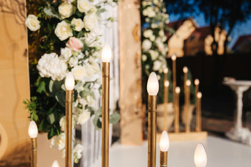 Details of wedding decoration. Wedding ceremony outside. Floral decoration. Gold, pink, powder and green color. Electronic candle