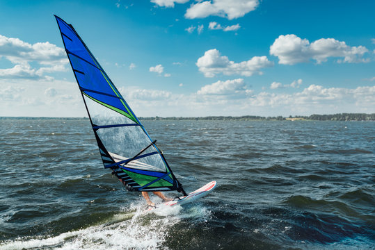 The Man Athlete Rides The Windsurf Over The Waves On Lake