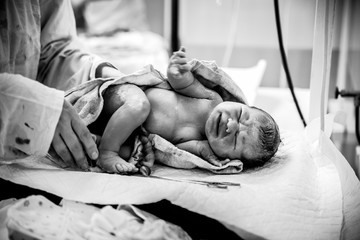 The obstetrician puts the newborn with the umbilical cord clamped on the changing table in the...
