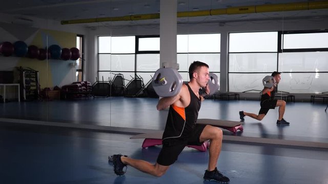 Young strong man in gym lifts weight having hard training workout