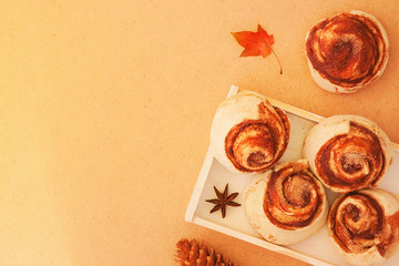 Fototapeta na wymiar Cinnamon rolls buns with cocoa and banana filling on a wooden breakfast table. Beautiful autumn concept. Top view, copy space.
