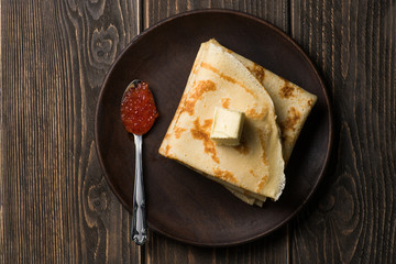 Top view of pancakes in pile with spoon of red caviar