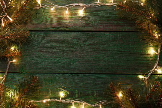 Photo of New Year's background with burning garland around perimeter, branches of spruce.
