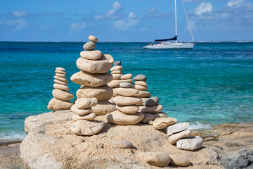 Stacks of stones in balance at a beach with yacht on a background