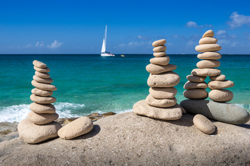 Stacks of stones in balance at a beach with yacht on a background