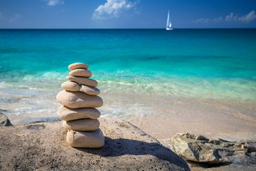 Stack of stones in balance at a beach with yacht on a background