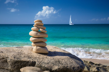 Fototapeta na wymiar Stack of stones in balance at a beach with yacht on a background