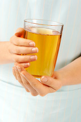 WOMAN HOLDING GLASS OF APPLE JUICE