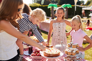 Children Serving On Cake Stall At Busy Summer Garden Fete