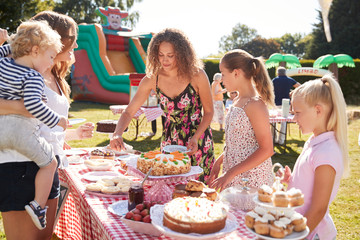 Children Serving On Cake Stall At Busy Summer Garden Fete