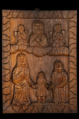 Fototapeta na wymiar Naive or folk wood carving bas relief plaque representing Presentation of the Blessed Virgin Mary or The Entry of the Most Holy Theotokos into the Temple subject. Isolated on black.