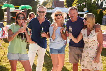 Portrait Of Mature Friends Enjoying Drinks At Summer Garden Fete