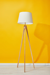 Minimalistic floor lamp near bright yellow wall