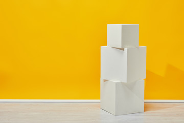 simple white plaster cubes arranged vertically near yellow wall