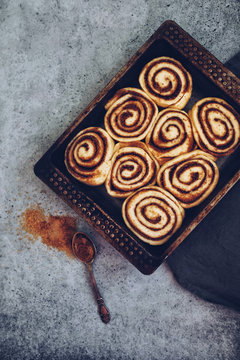 Traditional cinnamon buns in a baking sheet on stone background