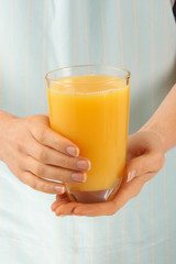 WOMAN HOLDING GLASS OF ORANGE JUICE