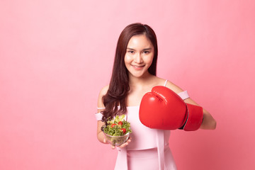 Young Asian woman with boxing glove and salad.
