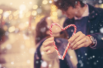 Romantic couple holds a holiday christmas candy cane heart