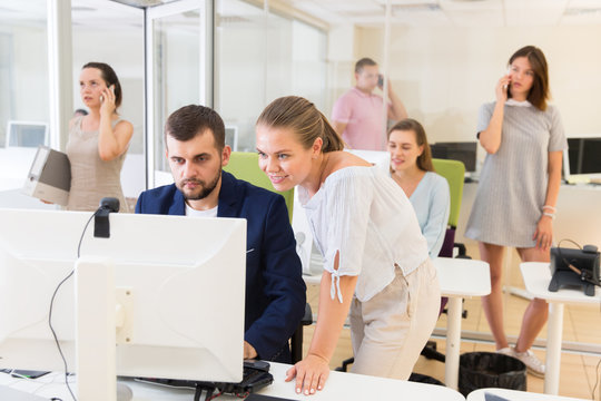 Young business woman helping  to guy coworker working at computer