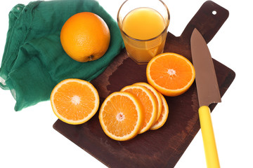 Culinary concept. Juicy fresh oranges on a cutting wooden board, green napkin and a glass of orange juice.