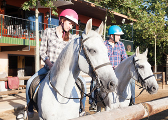 Mature couple in helmets  learn to riding horse at farm outdoor