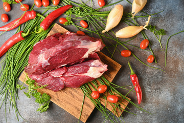 Fresh dark meat with ingredients for cooking on brown wooden cutting board. Hunting composition. Wildanimal hunting.