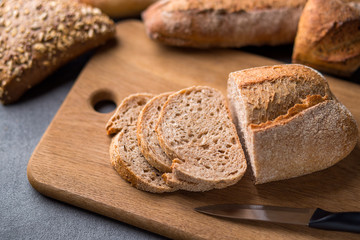 Sliced bread on the grey stone table, knife, close up.