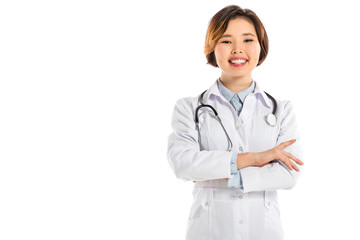 smiling female doctor with stethoscope and arms crosses looking at camera isolated on white