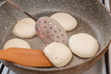 Fry fritters at home in the pan. Cooking pastries. Stand near the stove. View from above.