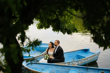 Foto op Canvas Beautiful bride and handsome groom posing in boat on lake © hreniuca
