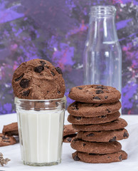 full glass of milk and round chocolate chip cookies