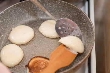 Fry fritters at home in the pan. Cooking pastries. Stand near the stove. View from above.