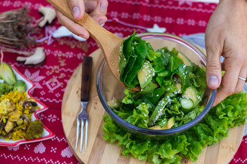 Spinach avocado fresh salad with Christmas red stars. Christmas food on red teblecloth