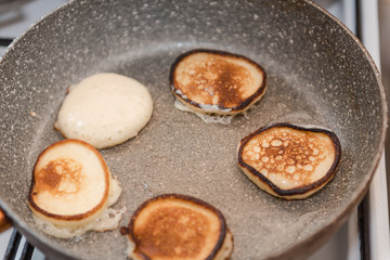 Fry fritters at home in the pan. Cooking pastries. Stand near the stove. View from above.