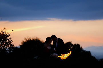 Obraz na płótnie Canvas Beautiful wedding couple posing in nature with fire