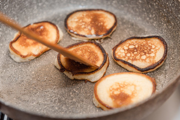 Fry fritters at home in the pan. Cooking pastries. Stand near the stove. View from above.