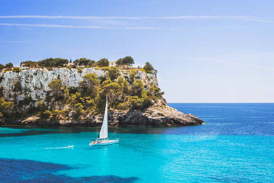 Fototapeta Beautiful bay with sailing boat yacht, Cala Galdana, Menorca island, Spain. Yachting, travel and active lifestyle concept