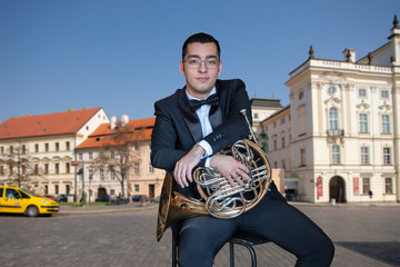 French horn player. Hornist playing brass orchestra music Portrait on the background of the city