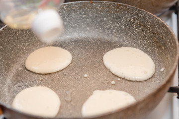 Fry fritters at home in the pan. Cooking pastries. Stand near the stove. View from above.