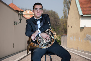 French horn player. Hornist playing brass orchestra music Portrait on the background of the city