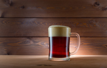 Glass of golden beer on wooden background