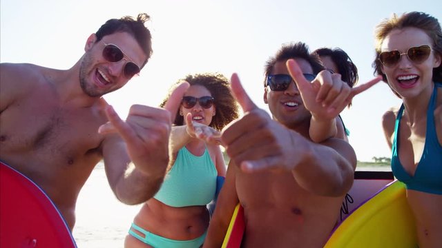 Portrait of multi ethnic friends in swimwear with bodyboards enjoying the beach 