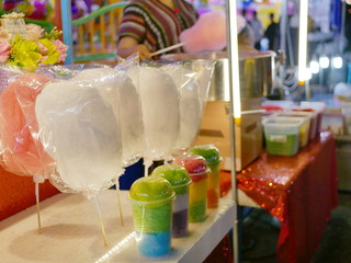 Colorful delicious cotton candy in cups and bags being displayed for sale in a night food fair