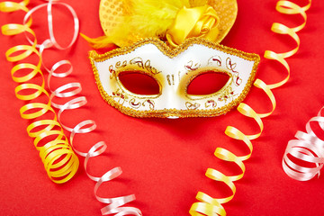 Yellow and white carnival mask on red background.