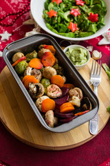 Hot baked, roasted, grilled vegetables in metal baking form. Beetroot, carrot, mushrooms, pumpkin, brussels sprouts with avocado dip sauce. Vegan red Christmas lunch, vegetarian dinner, healthy food