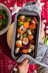Hot baked, roasted, grilled vegetables in metal baking form. Beetroot, carrot, mushrooms, pumpkin, brussels sprouts with avocado dip sauce. Vegan red Christmas lunch, vegetarian dinner, healthy food