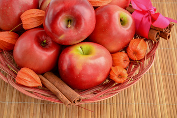 Basket with red apples in the company of Physalis and cinnamon