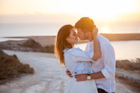 Young couple in love kissing each other with the spectacular view of the sea on sunrise