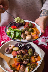 Woman hand adds sauce to baked, roasted, grilled vegetables. Beetroot, carrot, mushrooms, pumpkin, brussels sprouts with avocado dip sauce. Vegan lunch, vegetarian dinner